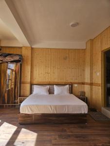 a bedroom with a large bed with wooden walls at Yul-Gal Homestay By StayApart in Kaza