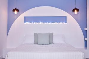 a white bed sitting under a lamp in a room at Orabel Suites Santorini (Adults Only) in Perivolos