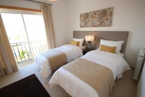 two beds in a room with a window at Josefa D’Óbidos Apartment in Casal da Lagoa Seca