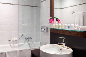 a bathroom with a tub, sink and mirror at Auteuil Manotel in Geneva