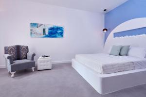 a white bedroom with a bed and a chair at Orabel Suites Santorini (Adults Only) in Perivolos