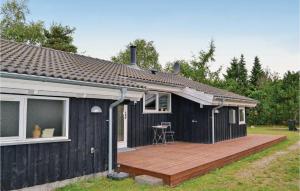 a small black house with a wooden deck at Holiday Home Røllikevej Knebel Ii in Knebel