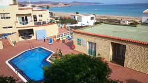 a view of a swimming pool next to a building and the beach at Apartment CasaVovo in Costa Calma