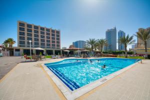 a swimming pool in a resort with buildings in the background at Ajman Beach Hotel in Ajman 