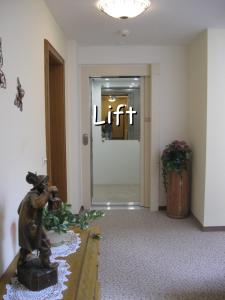 a lobby with a lift sign and a statue in the foreground at Pension Schlömmer in Sankt Gilgen
