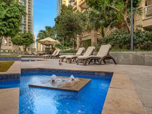 ドバイにあるRoyal Vista at 29 Boulevard - Dubai City & Burj Khalifa Views - Brand New Luxury 2BR Apartmentの中庭の噴水と椅子付きのプール