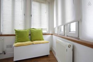 a white bench with green pillows in a room with windows at Heritage City - The Auld Pottery in Edinburgh