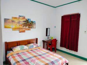 a bedroom with a bed and a desk with a red curtain at Tanah merah guest house in Singkawang
