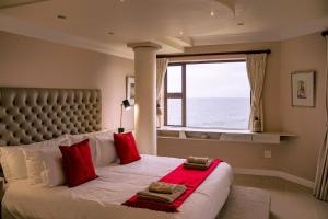 a bedroom with a large bed with red pillows and a window at Welsh Whales - Pet Friendly - Seafront Retreat in De Kelders