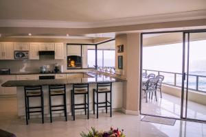 a kitchen with a counter with chairs and a view of the ocean at Welsh Whales - Pet Friendly - Seafront Retreat in De Kelders