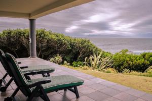 a patio with a table and chairs and the ocean at Welsh Whales - Pet Friendly - Seafront Retreat in De Kelders +28 photos