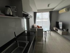 a kitchen and living room with a sink and a table at Condo Surin-Bangtao Beach in Ban Lum Fuang