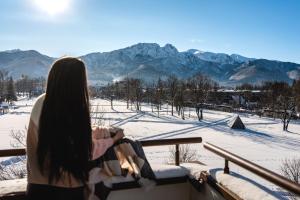 扎科帕内Hotel Helios 300m od Krupówek nowy BASEN od 12 lipca的站在一个阳台上的妇女,她从阳台上望着雪覆盖的群山