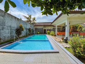 a swimming pool in the backyard of a house at Urbanview Hotel Kumala Banyuwangi by RedDoorz in Banyuwangi