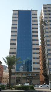 a tall building with a palm tree in front of it at Durrat Mina Hotel in Mecca