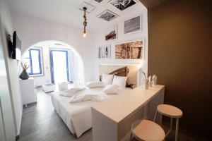 a white bedroom with a bed and a desk at Kaerati Apartments in Katapola