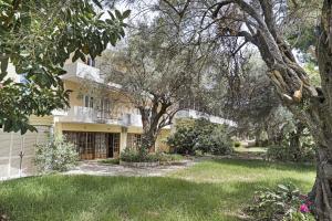an exterior view of a yellow house with trees at Mezoneta 4 in Nydri