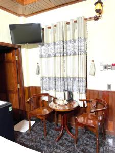 a room with a table and two chairs and a television at Nam Sông Hậu Hotel in Can Tho