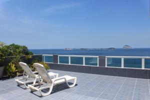 里约热内卢Hostel Vista do Mar的两把白色椅子坐在俯瞰着大海的庭院上