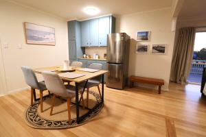 a kitchen with a table and a stainless steel refrigerator at Cozy Family Home 10min to Airport and Pet friendly in Auckland