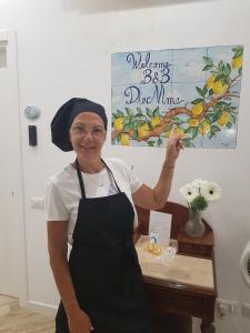 a woman in an apron standing in front of a sign at B&B DieMme Amalfi Coast in Vietri sul Mare