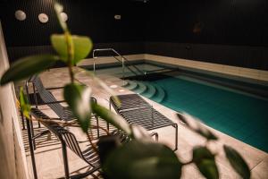 a pool with two chairs and a swimming pool at OTTO Hotel & Sun in Pāvilosta