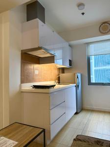 a kitchen with white cabinets and a refrigerator at The Bahamas & Maldives Suites at Azure Residences near Manila Airport in Manila