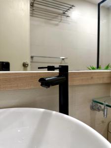 a bathroom sink with a black faucet at The Bahamas & Maldives Suites at Azure Residences near Manila Airport in Manila