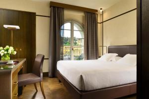 a hotel room with a bed and a desk and a window at Hotel Balestri - WTB Hotels in Florence