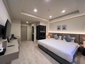 a bedroom with a large white bed and a television at Karon Boutique in Karon Beach
