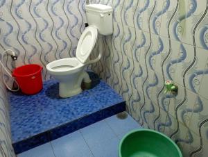 a bathroom with a toilet and a bucket at Hotel Grand Arputha in Velankanni +2 photos