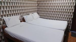 two beds in a room with white sheets and pillows at Hotel Grand Arputha in Velankanni