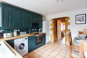 Una cocina con gabinetes verdes y lavadora y secadora. en Wellington Terrace, Private Garden, en Moreton-in-Marsh