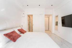 a white bedroom with a white bed with two red pillows at Honey Luxury Suite - close to Acropolis in Athens