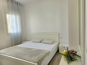 Lalzit BaySunny Beach Apartments - 253的一间白色的卧室,配有一张床和花瓶