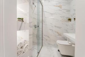 a bathroom with white marble walls and a glass shower at Honey Luxury Suite - close to Acropolis in Athens