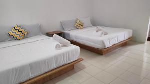 two beds sitting next to each other in a room at Laman Hanaz in Pantai Cenang