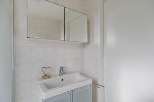a white bathroom with a sink and a mirror at Graspieper I Vrijstaand Huisje met Brede Tuin in Zwiggelte