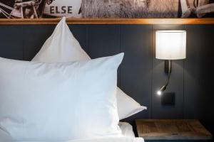 a bedroom with a bed with white pillows and a lamp at 4Hafenzeiten - NIE4 Else in Niendorf