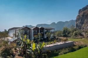 a house in a field with mountains in the background at Ailee Villa&Hotel TamCoc in Ninh Binh