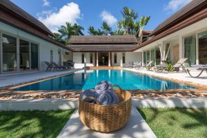 een rieten mand naast een zwembad bij Baan Batur in Koh Samui