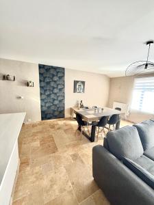 a living room with a couch and a table at Le Petit Phuket - Proche du centre ville de Mâcon - Appartement confortable et calme - Stationnement facile à proximité in Saint-Laurent-sur-Saône +2 photos