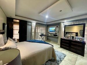 a bedroom with a large bed and a television at Good and Proper Guest Lodge in Vereeniging