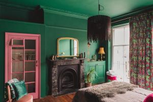 a green bedroom with a mirror and a fireplace at Ballarat House in Margate