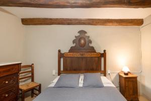 a bedroom with a bed with a wooden head board at Cal Masover De Vilardaga in Sagás +26 photos