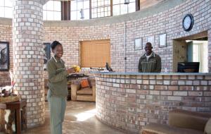 a woman standing in front of a brick bar at Etosha Village in Okaukuejo