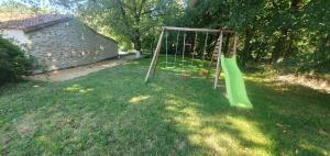 un parco giochi con altalena verde in un cortile di Maison 2/4 pers Les Herbiers proche Puy du Fou a Les Herbiers