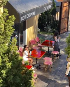 twee vrouwen zitten aan tafels buiten een koffieshop bij Hôtel De Da Phu in Da Lat