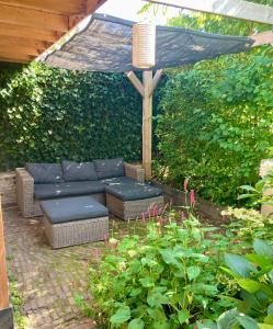 a patio with a couch and an umbrella at Modern historic home in a green setting in Hoevelaken