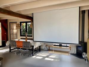 a large screen in a room with a table and chairs at Modern historic home in a green setting in Hoevelaken